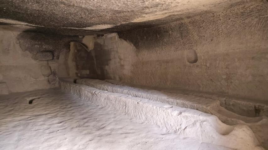 Kaya içine oyulmuş uzun masa ve oturma alanlarıyla birlikte Göreme Açık Hava Müzesi’ndeki yemekhane bölümü, duvarlarda is izleriyle görülüyor.